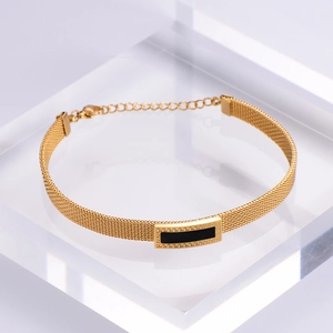 Detail of gold mesh titanium bracelet featuring a black rectangle and meander pattern