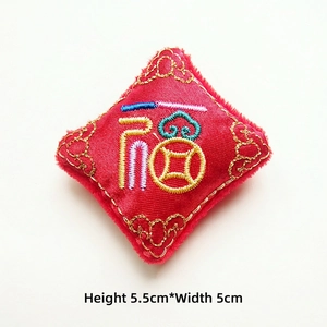 Detail view of a 5.5cm red satin Fu charm with colorful embroidery and golden scrolls