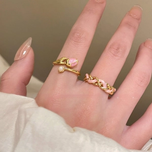 Detailed view of pink enamel tulip ring and woven chain band on a model's hand