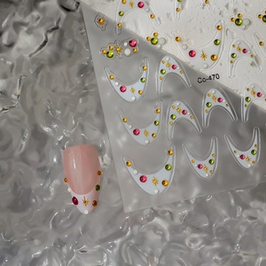 Macro shot of 5D macaron star nail stickers with colorful rhinestones on a pink nail
