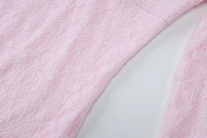 Détail du tissu en dentelle florale rose avec des motifs ajourés complexes sur la robe