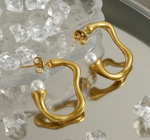 Vue macro de boucles d'oreilles irrégulières en acier doré 18k orné de perles blanches