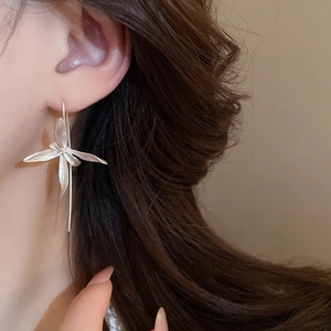 Close-up of silver iris flower drop earrings with elegant long tassel chain on model