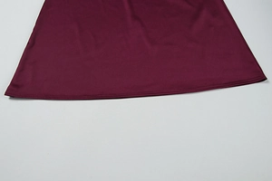 Detailed close-up of the neat stitching and hem on a slim-fit burgundy summer dress