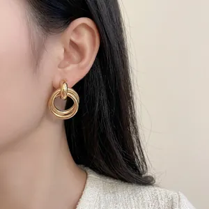 Minimalist triple layered gold hoop earrings shown on a model with metallic finish