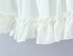 Detailopname van de witte ruches aan de zoom van een rok met hoge taille en textuur