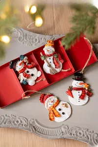 Detailed view of four resin snowman ornaments with festive scarves and mini accessories