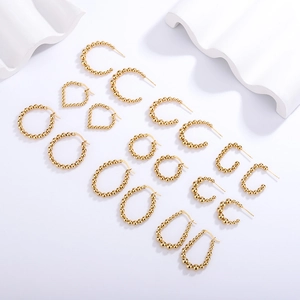 Set of minimalist golden stainless steel stud earrings in geometric shapes on white decor