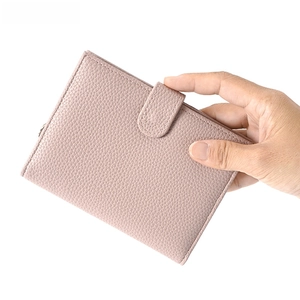 Detail of dust pink pebble leather passport holder with snap button strap closure