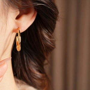 Close-up of model wearing 18K gold plated twisted C-shape earrings with zircon inlay