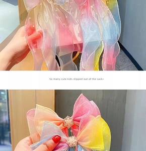 Detail of gradient rainbow organza hair bow with faux pearls and metal clip for girls