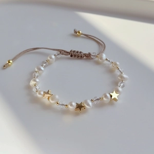 Detail of adjustable woven bracelet with natural freshwater pearls and gold star charm