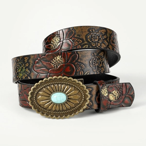 Macro detail of bohemian brown leather belt with floral embossing and turquoise buckle