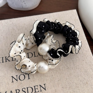 Close-up of black and white polka dot scrunchies with elegant pearl and lace trim