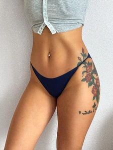 Detail of dark blue low-waist thong with ultra-thin side straps on model with tattoos