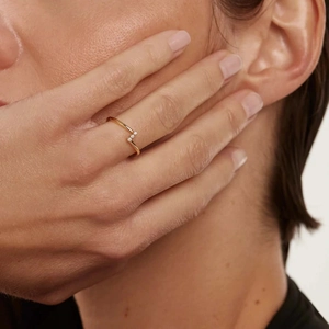 Detail of elegant V-shaped gold ring with three zircons worn on index finger