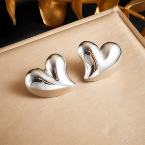 Polished silver stainless steel heart earrings on a luxury golden silk background