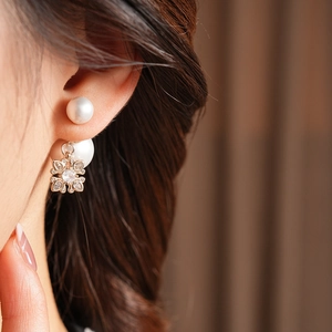 Close-up of double-sided gold clover pearl earring set with shimmering zircons