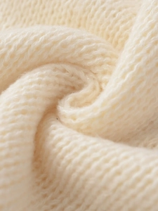 Detailaufnahme der groben Strickstruktur aus weichem, cremeweißem Wollstoff