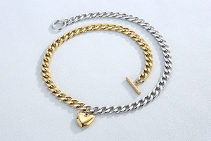 Detail of two-tone gold and silver Cuban chain necklace with heart pendant and OT buckle