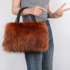 Detail view of orange-brown faux fur tote bag with black handles held by a model