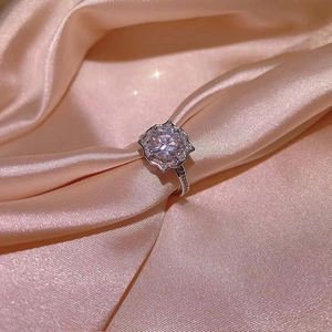 Macro view of silver flower ring with round zircon cluster on champagne silk
