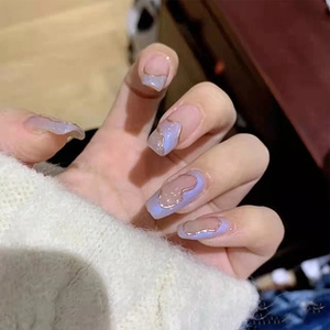 Detail shot of light blue press-on nails with 3D bow charms and French tip art design