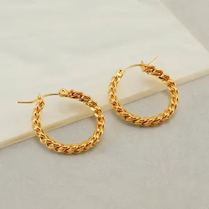 Elegant gold twisted hoop earrings with polished finish on a marble background