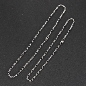Detailed view of silver titanium steel square link chains with lobster clasp on black background