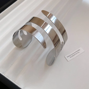 Macro detail of high-polish silver geometric double-layered crisscross open bangle