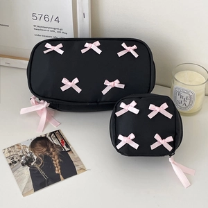 Macro view of black cosmetic bags with pink satin bows and decorative silk ribbons