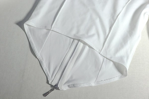 Detailed view of the white structured crop top with vertical seams and a metal zipper closure