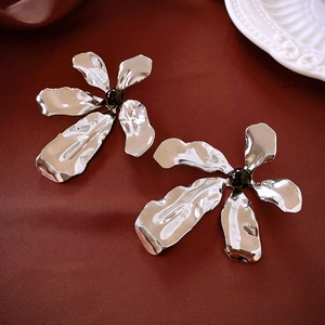 Detail of silver flower earrings with hammered texture and black center bead on silk