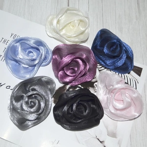 Detailed view of pearlescent fabric rose hair ties in seven assorted shimmer colors