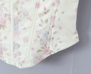 Detail of the sheer mesh fabric with purple floral print and delicate stitching on a corset