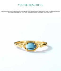 Macro shot of vintage gold ring featuring an oval blue topaz and engraved leaf details