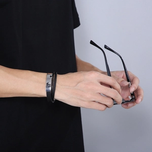 Dettaglio del bracciale multistrato in pelle nera da uomo con chiusura in metallo e stelle