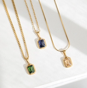 Dettaglio di collane placcate in oro con pietre quadrate color smeraldo, blu e champagne