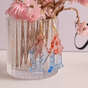 Orecchini sfumati rosa e blu con design a luna e stelle appesi a un vaso di vetro
