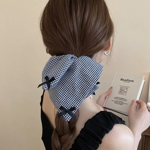Detail of black and white plaid bow hair scrunchie worn on a female hairstyle