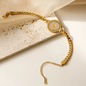 Golden stainless steel chain bracelet with a vintage portrait coin charm on stone background