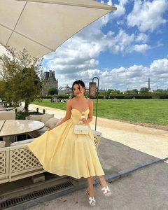 Close-up of yellow strapless corset dress with a large bow detail in a scenic Paris setting