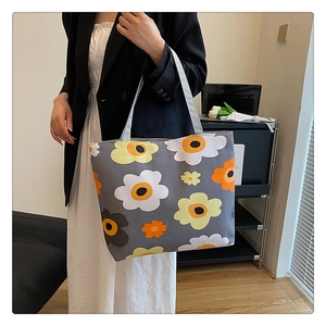 Detail of large canvas tote bag with floral print carried by a model in a cozy setting