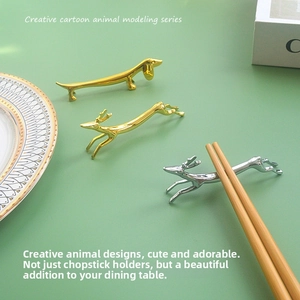 Creative gold and silver metal chopstick rests in deer and dachshund shapes on ceramic plate