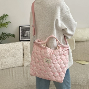 Sac fourre-tout matelassé rose avec motif lapin porté par un mannequin dans un intérieur