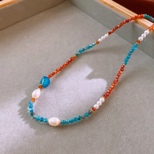 Close-up of Baroque pearls with red and blue faceted stones on a jewelry display tray