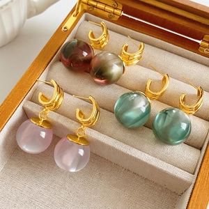Spherical resin dangle earrings in purple, green, and red displayed in a jewelry box