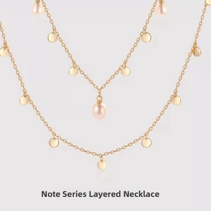 Detail of layered gold-plated necklace with sequins and a glossy freshwater pearl