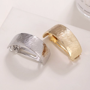 Brushed metal curved ponytail hair clips in gold and silver finish on white stand