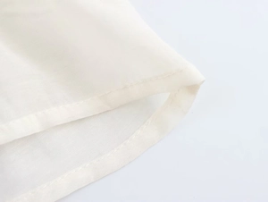 Close-up of cream lace stitching and fine fabric texture on the shirt hemline